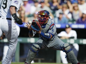 Los Angeles Dodgers catcher Yasmani Grandal, back, fields the throw from left fielder Matt Kemp to put out Colorado Rockies' Charlie Blackmon as he tries to score on a fly ball hit by Carlos Gonzalez in the first inning of a baseball game Saturday, June 2, 2018, in Denver.