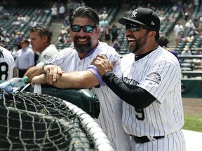 Retired Colorado Rockies first baseman Todd Helton, left, jokes with former teammate and third baseman Vinny Castilla as they watch batting practice during picture day for the Rockies before a baseball game against the Miami Marlins Saturday, June 23, 2018, in Denver.