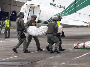 In this handout photo provided by the Colombian National Police, police carry the body of one of three Ecuadorean press workers kidnapped and killed in the conflictive border region with Ecuador, as they arrive to the airport in Palmira, Colombia, Friday, June 22, 2018. The three men, employees with the El Comercio newspaper, were investigating a rise in drug-fueled violence along the Colombia-Ecuador border when they disappeared in March. In a proof-of-life video the men identified their captors as members of a dissident front of the now disbanded Revolutionary Armed Forces of Colombia. (Colombian National Police via AP)