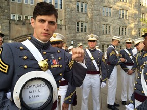 In this May 2016 photo provided by Spenser Rapone, he displays a sign inside his hat that reads "Communism will win," after graduating from the United States Military Academy at West Point, N.Y.