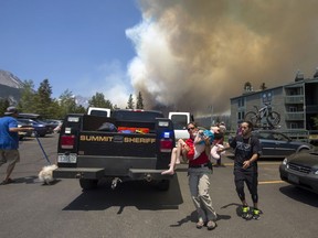 Erin Sirek with the Summit County Sheriff's Department Residents carries a boy as residents evacuate their homes from a wild fire approaching in the Wildernest neighborhood near Silverthorne, Colo., Tuesday, June 12, 2018.