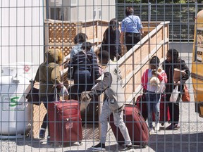 A group of asylum seekers arrive at the temporary housing facilities at the border crossing Wednesday May 9, 2018 in St. Bernard-de-Lacolle, Quebec.