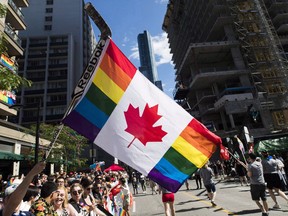 A man holds a flag on a hockey stick during the Pride parade in Toronto, Sunday, June 25, 2017. The first court challenge to an Alberta law that bars schools from telling parents when their children join gay-straight alliances carries some echoes of the debate over legalizing same-sex marriage more than a decade ago, according to one LGBTQ advocate.