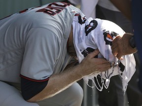 Minnesota Twins' Brian Dozier has a cold wet towel applied to his head during the seventh inning of a baseball game Chicago Cubs Saturday, June 30, 2018, in Chicago. Temperatures at Wrigley Field climbed into the mid 90's with a heat index over 100 degrees.