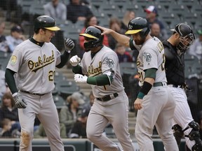 Oakland Athletics' Franklin Barreto, center, celebrates with Mark Canha, left, and Jonathan Lucroy after hitting a three-run home run against the Chicago White Sox during the eighth inning of the first game of a baseball doubleheader in Chicago, Friday, June 22, 2018.
