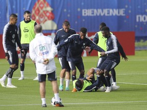 France's Antoine Griezmann, Thomas Lemar and Ousmane Dembele joke to Corentin Tolisso, laying down the field, during a training session of France at the 2018 soccer World Cup in Glebovets, Russia, Monday, June 11, 2018.