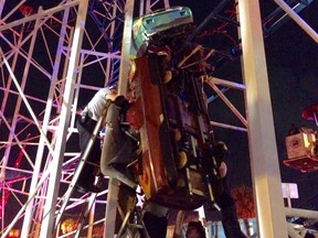 Firefighters working as fast as they can to rescue two riders that are in a dangling rollercoaster car.