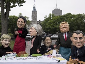 Activists stage a demonstration while wearing masks of G7 leaders, from left to right, Angela Merkel, Justin Trudeau, Theresa May, Shinzo Abe, Donald Trump, and Emmanuel Macron prior to the G7 Summit in Quebec City on Thursday, June 7, 2018.