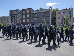 Riot police officers march toward a group of protestors demonstrating during the G7 Summit in Quebec City on Friday, June 8, 2018.