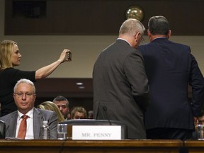 After invoking his right under the Fifth Amendment not to answer questions, former USA Gymnastics president Steve Penny, right, walks from a Senate Subcommittee on Consumer Protection, Product Safety, Insurance, and Data Security hearing on Capitol Hill in Washington, Tuesday, June 5, 2018. The hearing is on "Preventing Abuse in Olympic and Amateur Athletics: Ensuring a Safe and Secure Environment for Our Athletes." Amy Moran, left, uses a smart photo to record Penny's exit.