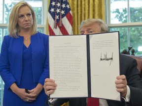 President Donald Trump holds up an executive order he signed to end family separations, during an event in the Oval Office of the White House in Washington, Wednesday, June 20, 2018. Looking on is Homeland Security Secretary Kirstjen Nielsen, left.