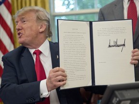 President Donald Trump holds up the executive order he signed to end family separations at the border, during an event in the Oval Office of the White House in Washington, Wednesday, June 20, 2018.