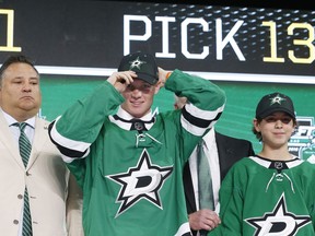 Ty Dellandrea, second from left, puts on a cap after being selected by the Dallas Stars during the NHL hockey draft in Dallas, Friday, June 22, 2018.