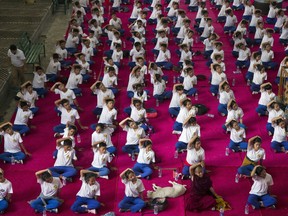 A dog sleeps in the midst of exile Tibetan school children who participate in a joint yoga session at the Tsuglakhang temple to mark the International Yoga Day in Dharmsala, India, Thursday, June 21, 2018. Dozens of school children and government officials participated in the event.
