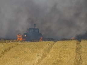 FILE - In this Friday, June 1, 2018 file photo, an Israeli tractor works to extinguish a fire started by a kite with an incendiary device launched from Gaza, in a wheat field of Kibbutz Mefalsim, near the Israel Gaza border. Israeli border towns are coping with incendiary kites and balloons that have not been lethal but have devastated their farmlands and nature reserves. Since March 30 near-weekly Palestinian border protests have torched some 7,000 acres (2,800 hectares) of Israeli land and caused some $2 million in damages, while Israeli forces have killed more than 120 Palestinians and wounded over 3,800.