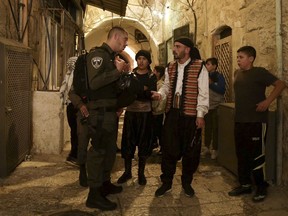 In this Tuesday, June 5, 2018 photo, traditionally dressed Palestinian public wakers, known as musaharati, are stopped by the Israeli border police in the Jerusalem's Old City. Public wakers walk through the Old City chanting, singing, and playing drums in order to wake those who are fasting during the Muslim holy month of Ramadan. During Ramadan Muslims worldwide abstain from drinking, smoking and eating during daytime.