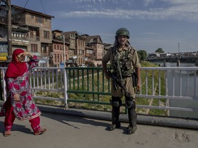 An Indian paramilitary soldier stands guard as a Kashmiri woman walks past in Srinagar, Indian controlled Kashmir, Wednesday, June 20, 2018. India's federal government has taken direct control of Kashmir state after the ruling Hindu nationalist party ended its long-troubled alliance there with a Kashmiri political party.
