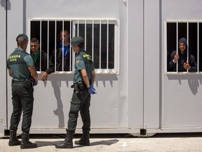 Guardia Civil officers speak with migrants confined at a makeshift emergency center at the port of Barbate, southern Spain, after being rescued by Spain's Maritime Rescue Service in the Strait of Gibraltar, Wednesday, June 27, 2018. Authorities in Southern Spain are setting up makeshift emergency centers for African migrants rescued in waters of the Mediterranean Sea as they hasten to cross into Europe.