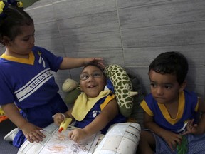 In this May 8, 2018 photo, a fellow student gently strokes Jose Wesley Campos, who was born with the Zika-caused microcephaly birth defect, at an early education daycare center in Bonito, Brazil. Jose, who will be 3 in September, attends the daycare two days a week.