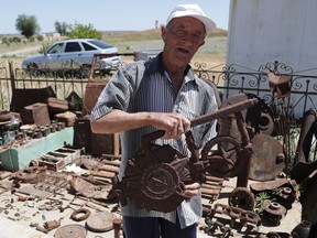 In this photo taken on Sunday, June 17, 2018, 72 year old Vitaly Danilkin holds up memorabilia and remains of battles that took place near Stalingrad, in Rossoshka, Russia. Vitaly Danilkin takes care for a cemetery some 40 miles northwest of Volgograd in Rossoshka, for German soldiers who perished at Stalingrad and nearby Rostov-on-Don, as well as a Soviet cemetery on the other side of the road. Nearly 60 years since it changed its name to Volgograd, the Russian city once called Stalingrad and its bloody history loom large even in the midst of the fun and football of the World Cup.