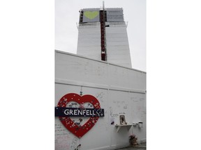 Banners, one with a green heart, are unveiled on the outside of Grenfell Tower in west London, Thursday, June 7, 2018, almost a year after a fire killed 72 people in the apartment block.
