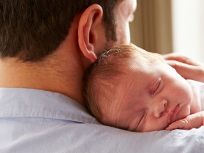 Father at home holding sleeping newborn baby daughter. “Dad genes” are particles on the sex-specific Y chromosome, long mocked for being a stunted clump of mostly useless nucleic waste but lately revealed as man’s fastest friend, essential to the health of male bodies and brains no matter the age.