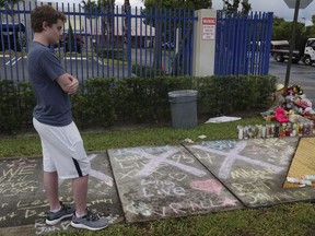 A fan of rap singer XXXTentacion pauses by a memorial, Tuesday, June 19, 2018, outside Riva Motorsports in Deerfield Beach, Fla., where the troubled rapper-singer was killed the day before. The 20-year-old rising star, whose real name is Jahseh Dwayne Onfroy, was shot outside the motorcycle dealership on Monday, June 18, when two armed suspects approached him, authorities said.