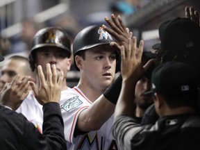 Miami Marlins' Brian Anderson is congratulated in the dugout after scoring on a double by JT Riddle during the third inning of a baseball game against the San Francisco Giants, Tuesday, June 12, 2018, in Miami.