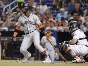 San Francisco Giants' Andrew McCutchen, left watches after hitting a RBI double to score Gorkys Hernandez during the fifth inning of a baseball game against the Miami Marlins, Monday, June 11, 2018, in Miami. At right is Miami Marlins catcher J.T. Realmuto.