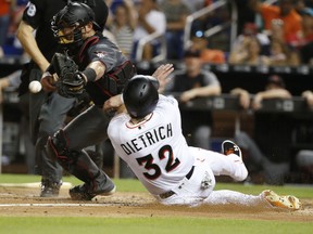 Miami Marlins' Derek Dietrich (32) slides into home safely as Arizona Diamondbacks catcher Jeff Mathis waits for the throw during the fourth inning of a baseball game, Monday, June 25, 2018, in Miami. Dietrich and Dan Straily scored on a double by Brian Anderson.