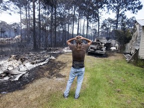 FILE- This June 25, 2018 shows Faron Bryant looking over his property after wildfires swept through his neighborhood on Ridge Road in Eastpoint, Fla. Bryant's home only lost its siding, but his workshop, a truck and boat were destroyed. Adam Putnam, Florida's agriculture commissioner, said Wednesday, June 27, 2018, that a controlled burn by state contractors sparked a wildfire that destroyed 36 homes and burned more than 800 acres.