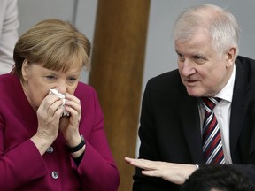 FILE - In this March 21, 2018 file photo German Chancellor Angela Merkel, left, and German Interior Minister Horst Seehofer, right, talk during a meeting of the German federal parliament, Bundestag, in Berlin.
