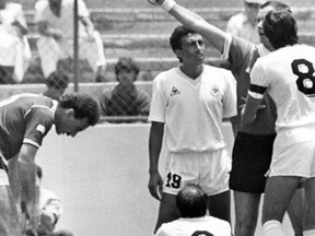 FILE - In this June 13, 1986 filer, French referee Joel Quiniou, rear right, shows the red card to Uruguayan player Jose Batista, No. 6, for a bad tackle on Scotland's Gordon Strachan, on the floor left, just one minute after the start of the Football World Cup match between Scotland and Uruguay in Mexico City, Mexico. The first red card of the Russia 2018 World Cup tournament has been awarded against Colombia midfielder Carlos Sanchez for handling a goal-bound shot in the area in the third minute against Japan. Shinji Kagawa slotted the resultant penalty to give Japan an early 1-0 lead in the World Cup Group H game.