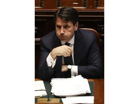 FILE - In this Wednesday, June 6, 2018 filer, Italian Premier Giuseppe Conte puffs away ahead of a confidence vote on the government programme, in Rome.  Italy will be represented at this week's summit of the world's wealthiest democracies by a political novice whose powers in the new populist government remain to be tested:  At best, as an executor of a program he didn't help draft, at worst, as a mediator between two disparate political blocs joined in a marriage of convenience.