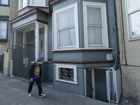 A man walks past a multi-unit property where a woman was charged with murder in the slaying of her roommate in San Francisco, Thursday, June 7, 2018. A dismembered body was discovered in oozing plastic bags inside a maggot-filled storage container at their home, prosecutors said Wednesday.