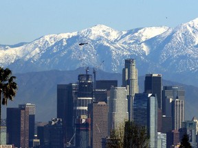 File - In this Jan. 12, 2016 file photo, the snow-capped San Gabriel Mountains stand as a backdrop to the downtown Los Angeles skyline. An initiative that seeks to split California into three states is projected to qualify for the state's November 2018 ballot.  The latest proposal for splitting up the Golden State  would create the states of Northern California, Southern California and a narrow central coast strip retaining the name California. Even if voters approve the initiative an actual split would still require the approval of the state Legislature and Congress.