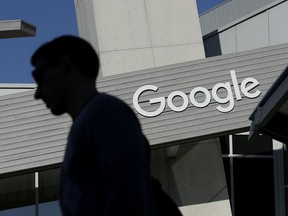 FILE - In this Nov. 12, 2015, file photo, a man walks past a building on the Google campus in Mountain View, Calif. Voters in a Northern California city will decide whether Google and other tech companies should help pay for the traffic headaches and other problems that have arisen as their workforces have swelled during the past decade. The city council in Mountain View, California, voted Tuesday, June 26, 2018, to place a measure on the November ballot asking residents to authorize taxing businesses between $9 and $149 per employee.