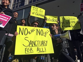 FILE - In this April 14, 2017, file photo, protesters hold up signs outside a courthouse where a federal judge was to hear arguments in the first lawsuit challenging President Donald Trump's executive order to withhold funding from communities that limit cooperation with immigration authorities in San Francisco. After repeatedly suing the Trump administration over U.S. immigration policies, California will find itself in an unusual position Wednesday, June 20, 2018: defending protections for people in the country illegally against a court challenge by the federal government. U.S. Judge John Mendez in Sacramento will hear arguments from attorneys for the state and the U.S. Justice Department about a federal request to block three California laws.