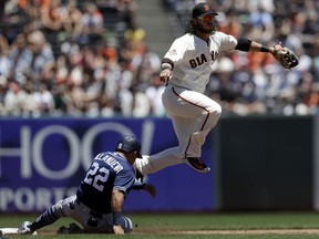 San Francisco Giants shortstop Brandon Crawford, top, completes a double play over San Diego Padres' Christian Villanueva (22) on a ground ball by Jose Pirela during the second inning of a baseball game Saturday, June 23, 2018, in San Francisco.
