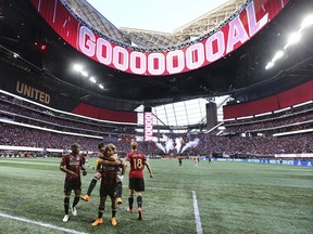 FILE - In this June 2, 2018, file photo, the roof of Mercedes-Benz Stadium is open as Atlanta United forward Josef Martinez celebrates his goal against the Philadelphia Union on a penalty kick while Miguel Almiron jumps on his back during an MLS soccer match in Atlanta. The 2026 World Cup will return to the U.S. for the first time since 1994. Atlanta's new Mercedes-Benz Stadium was shown prominently in the video used in the North American pitch for the bid. (Curtis Compton/Atlanta Journal-Constitution via AP, File)/