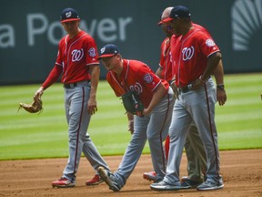Washington Nationals pitcher Jeremy Hellickson reaches down to his leg as he comes out of a baseball game after leaping for a wild throw by first baseman Mark Reynolds (14) on a ball hit by Atlanta Braves' Ozzie Albies during the first inning Sunday, June 3, 2018, in Atlanta.