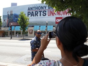 A woman takes a photograph of a billboard for the CNN television show "Parts Unknown" with American celebrity chef Anthony Bourdain, Friday, June 8, 2018 in Atlanta. Bourdain, 61, was found dead in his hotel room in France on Friday, while working on the series which features culinary traditions around the world.