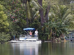 A couple looks out from a pontoon boat on one of the lakes at Silver Lakes Rotary Nature Park, Friday, June 8, 2018, in Davie, Fla. Authorities worked Friday to capture an alligator in a Florida pond after a witness' report led police to believe the animal may have dragged a woman into the water.
