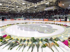 Flowers lie at centre ice as people gather for a vigil at the Elgar Petersen Arena, home of the Humboldt Broncos, on April 8 to honour the victims of a fatal bus accident in Humboldt, Sask.