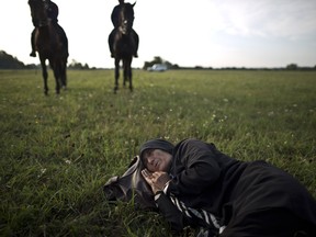 In this Sept. 16, 2015 file photo an elderly Afghan migrant rests on the ground of a field while she and others being detained by Hungarian police on horses for sneaking through Hungary's border fence with Serbia, in Asotthalom, southern Hungary.