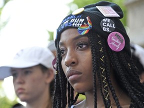 Tyra Hemans, an alumnae of Marjory Stoneman Douglas High School in Parkland, Fla., watches an art performance by Manuel Oliver at a peace rally and march, Friday, June 15, 2018, in Chicago. A group of Florida high school shooting survivors started their nationwide bus tour registering young voters to help accomplish their vision for stricter gun laws at the rally on Chicago's South Side.