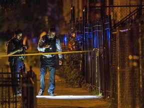 In this Thursday, June 14, 2018 photo, Chicago Police officers investigate the scene where two people were shot in Chicago. A 12-year-old Michigan girl spending the summer in Chicago was fatally shot at the scene, hours after attending a cousin's eighth-grade graduation. Family members at the hospital identified the girl as She'nyah O'Flynn of Covert, Michigan. She and a man who was injured were apparently unintended victims of gunfire from a nearby party. Police say there have been no arrests.
