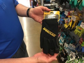 In this Thursday, June 14, 2018 photo, Mark Driscoll, owner of the Ace Hardware in Sugar Grove, Ill., holds a pair of gloves like the type he tried on recently and discovered a man's ring in one of the fingers. He's now trying to find the owner of the ring but so far has had no luck.