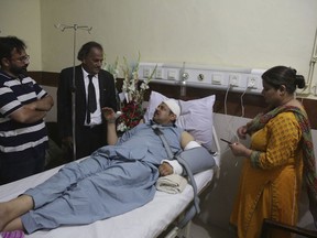 In this Wednesday, June 6, 2018 photo, Pakistani TV anchorman Asad Kharal talks to visitors after he was stabbed by masked men near his residence, at a hospital in Lahore, Pakistan. The Vienna-based Independent Press Institute, an international watchdog, said in a report released Monday, June, 18, 2018, that Pakistan's military is strong-arming the media in an attempt to stifle criticism of its behind-the-scenes political power ahead of next month's elections. The report documented a nationwide campaign of intimidation, including everything from threats to abductions.
