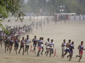 FILE- In this April 26, 2016 file photo, candidates, many barefoot and unable to afford running shoes, run to pass a fitness test during a recruitment drive for the Uttar Pradesh state police, in Allahabad, India. Police in northern India have broken up a gang that promised professional test-takers and high-tech listening devices to help applicants pass a two-day test to become police constables, officials said Tuesday.